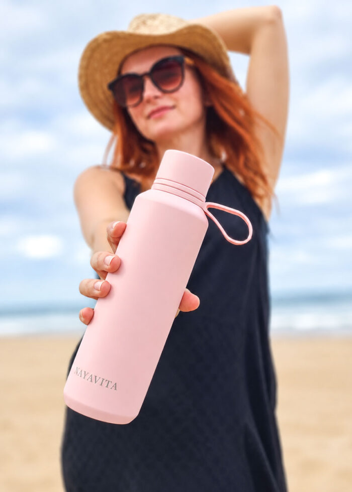 NAYAVITA žena na pláži drží růžovou termolahev na teplé a studené nápoje Pink